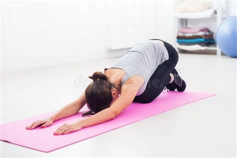 Fit Woman Bending Over On Mat Doing Pilates Exercise At Home In The