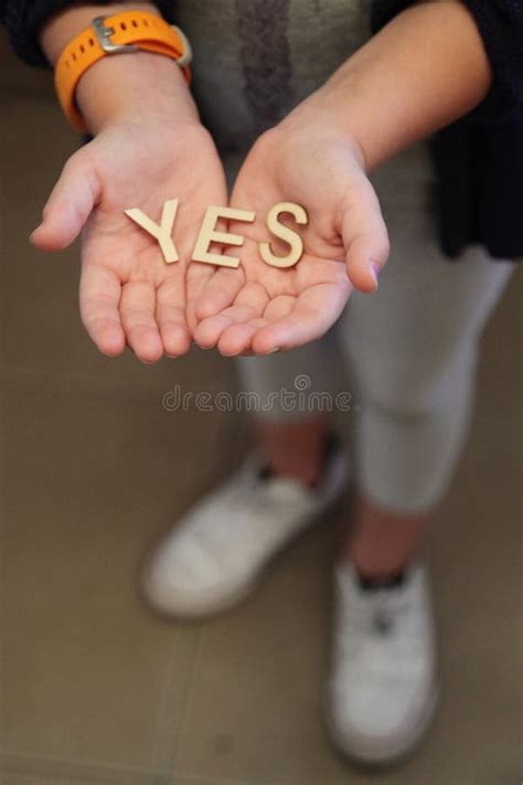 A Single Child Opening Her Hands With Wooden Letters Forming The Word