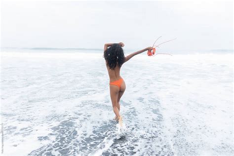 A Young Woman Seen From The Back Celebrating Her Walking Into Teh Ocean In Bali By Stocksy