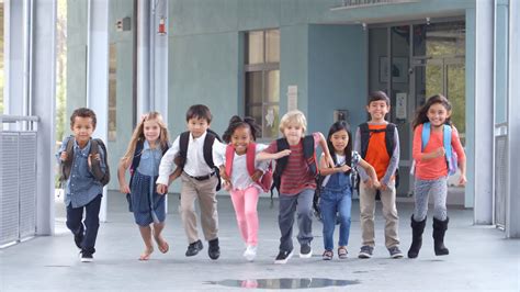 Group Of Elementary School Kids Running In A School Corridor Stock