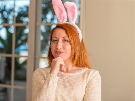 Redhead Woman Wearing Easter Rabbit Ears At Home Serious Face Thinking