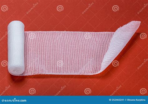 Rolled Out Roll Of Medical Bandage On Red Background Stock Image