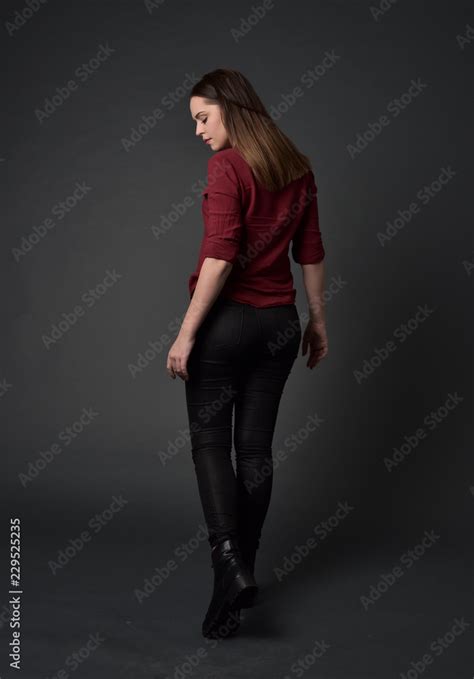 full length portrait of brunette girl wearing red shirt and leather pants standing pose facing