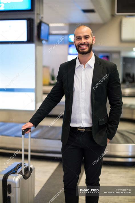 Portrait Of Businessman Standing With Luggage At Waiting Area In