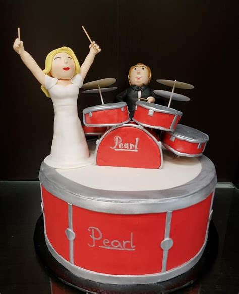 A Wedding Cake With A Drum Set And Bride And Groom Figurines On Top