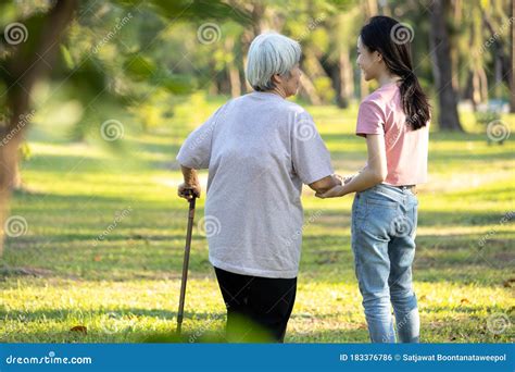 Old Elderly Using A Walking Stick To Help Her Walk Balanced With Her