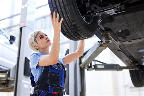 Female Auto Mechanic Fixing Car Mechanic Repairing Car On Lift In