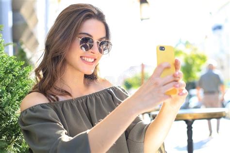 Young Pretty Brunette Woman Outdoors In Summer City Take A Selfie By Mobile Phone Stock Image
