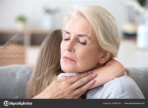 Loving sad grandmother embracing little girl comforting supporti Stock