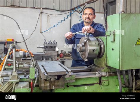 Blue Collar Machine Operator Working With Lathe Machine In A Factory