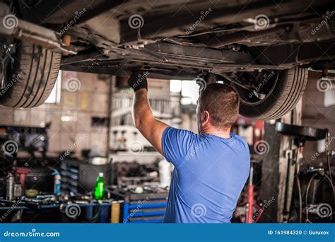 Auto Mechanic Repairer Checking Condition Under Car On Vehicle Lift