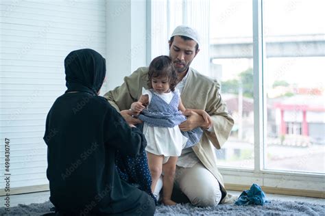Muslim Father And Mother In Traditional Dress Helping Dressing Their Daughter Happy Muslim