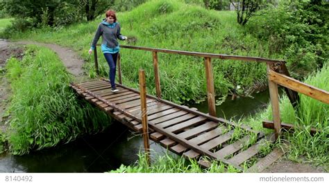 woman go across a l ittle river on a wood bridge stock video footage 8140492