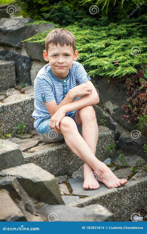 A Boy Of 8 Years Old Is Sitting On A Stone Staircase With Bare Feet In