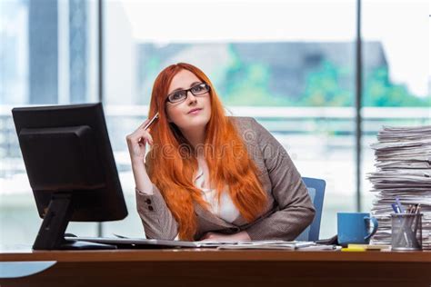 The Redhead Businesswoman Sitting At Her Desk In The Office Stock Image