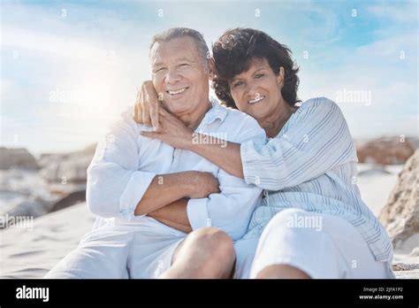 Portrait Of A Senior Mixed Race Couple Sitting Together On The Beach