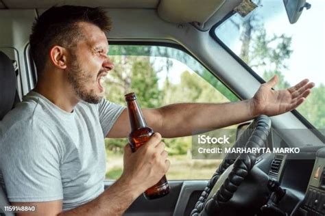 direksiyonda bir adam araba kullanırken elinde bir Şişe alkol tutuyor trafik kurallarını ihlal