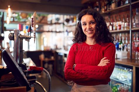 Portrait Of Smiling Female Bar Owner Standing Behind Counter Stock