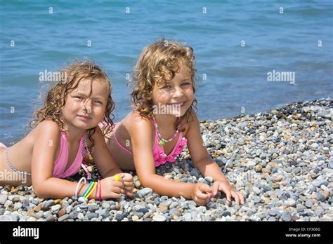 Zwei Hübsche Mädchen Auf Steinigen Strand In Der Nähe Von Meer Liegend