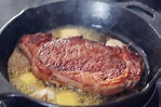 a piece of meat is cooking in a skillet on the stove with some oil