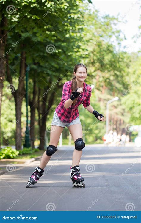 Girl On Rollerblades Sitting On A Bench In A Park And Putting On Inline Skates In A Sunny Bright