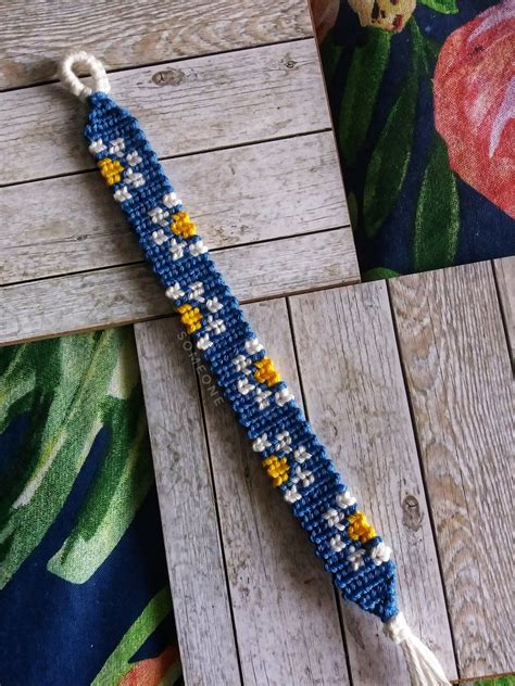 A Blue Beaded Bracelet With Yellow And White Flowers On It Sitting On