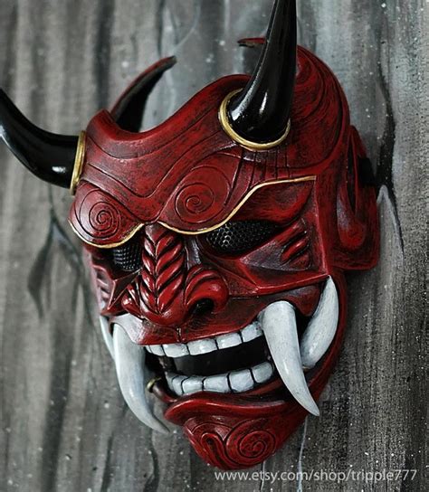 A Red Mask With Horns And Fangs On Its Face Is Hanging From The Wall
