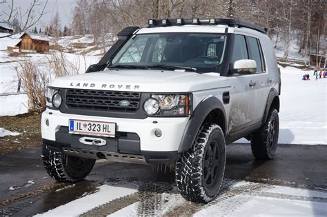 A White Land Rover Is Parked In The Snow
