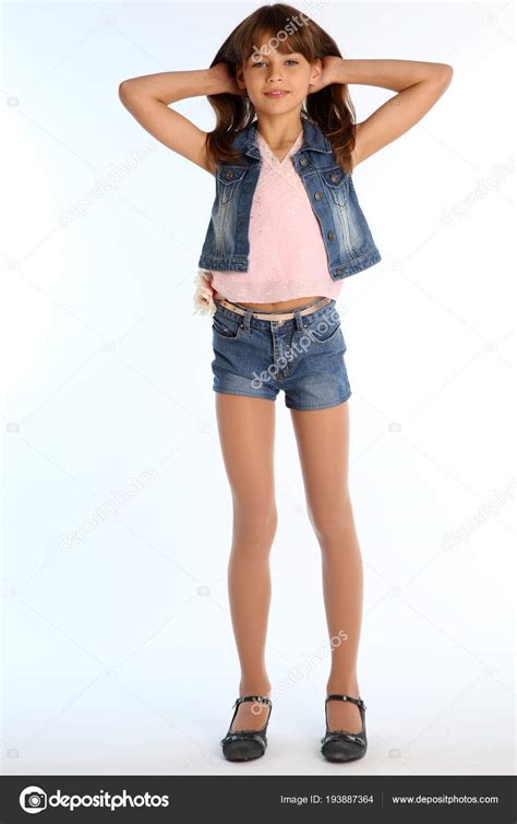 デニムのショート パンツで美しい少女は 完全な長さに立っています スレンダーな身体とストッキングの長い脚を持つエレガントな魅力的な子 カップル
