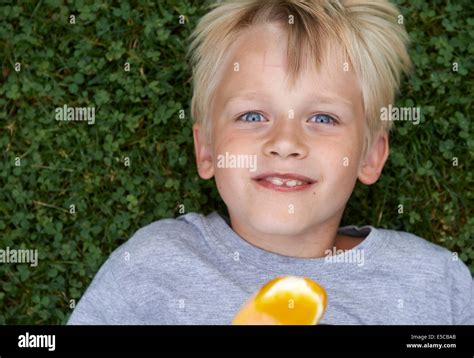 Blond Child 6 8 Year Old Boy Holds Lickling And Eating Yellow Ice