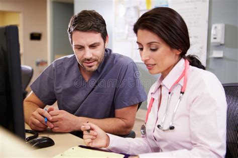 Female Doctor With Male Nurse Working At Nurses Station Stock Photo