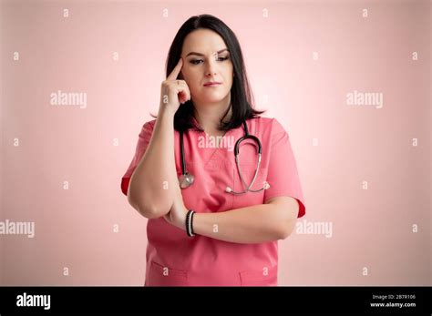 Portrait Of Beautiful Woman Doctor With Stethoscope Wearing Pink Scrubs Wondering Posing On A