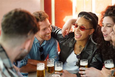 friends talking and having fun together in the bar drinking beers multicultural group of