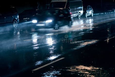 Blurred Car Driving On Night Street During Heavy Rain Stock Photo