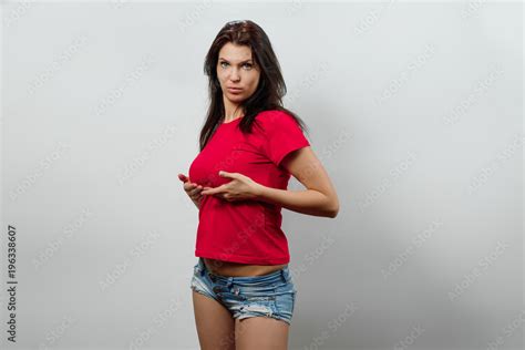 Young Beautiful Girl Stands Holding Her Breasts With Her Hands Isolated On A Light Background