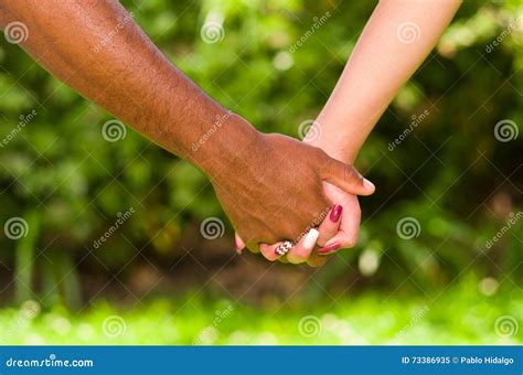 arms of interracial couple holding hands great love symbolic concept green garden background