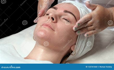 Portrait Of A Beautiful Girl On A Procedure In A Beauty Salon The Hands Of The Cosmetologist