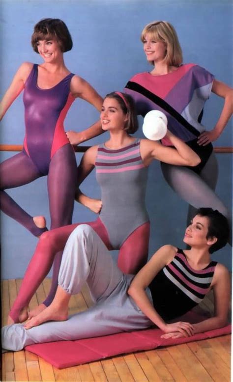 four women in bodysuits posing on a mat with one holding a white ball