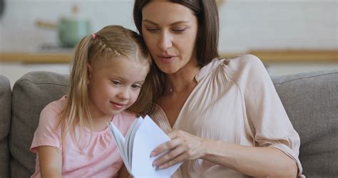 Focused Young Mother Reading Interesting Story To Daughter Stock Video