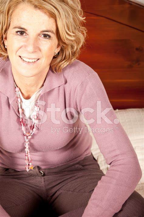 Happy Mature Woman Sitting On The Bed Stock Photo Royalty Free