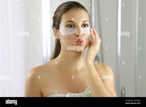 Attractive Woman Applying Anti Fatigue Under Eye Mask Looking And Kissing Herself In The Mirror