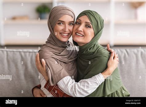 Happy Muslim Mother And Adult Daughter Hugging Wearing Hijab Indoor