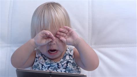 Baby Girl With Tablet Rubbing Her Eyes After Crying Stock Photo Image
