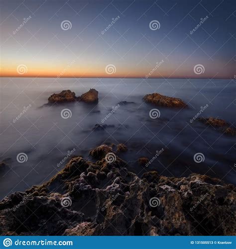 Beautiful Sunrise At Sea Shore And Wet Rocks In Water Soft Light Pink