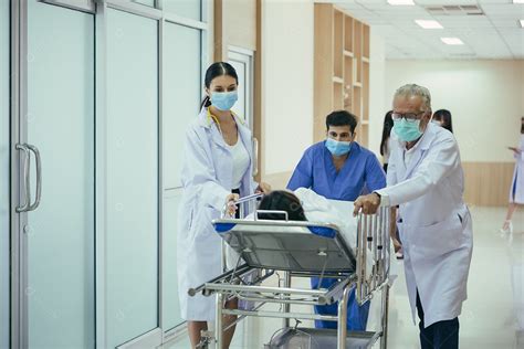Médico enfermeira e paramédicos carregando paciente na maca empurrando