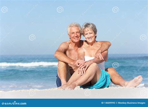 senior couple on holiday sitting on sandy beach stock image image of female male 14689995