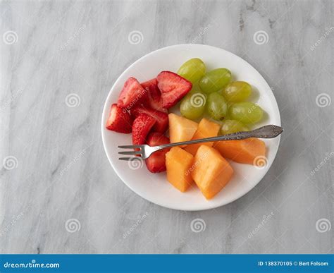 Assortment Of Fresh Fruit With A Fork On A White Plate Stock Image