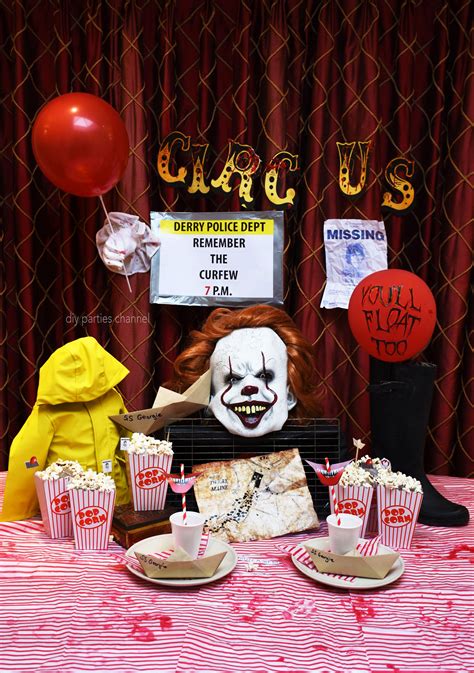 A Table Topped With Lots Of Cupcakes Next To A Creepy Clown Face Mask
