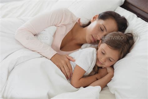 High View Of Caucasian Mother And Daughter Sleeping In Bed In Bedroom
