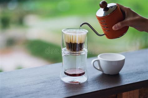 A Hand Pouring Hot Water From Kettle To Make Drip Coffee With Blurred Nature Background Stock